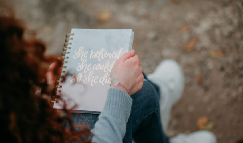 sustainable living planning: Photo of a woman holding a notebook with the text " she believed she could, so she did" Photo by Natalie Bond